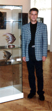 Евгений Вагнер на выставке рядом со своими работами.